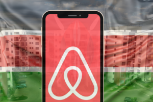 Foreground is a phone mockup with an Airbnb logo on the screen, background is a translucent Kenyan flag, further in the background are condominium (apartment) blocks as used in an article about AirBnB business in Kenya